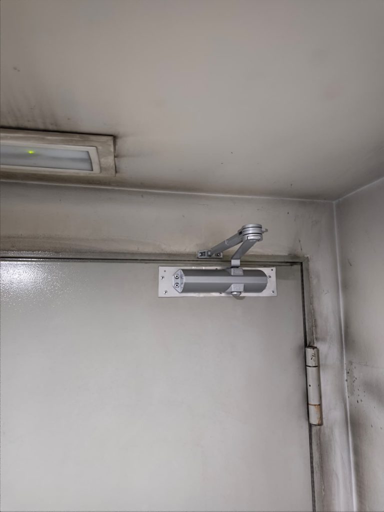Solución técnica a medida con soporte de aluminio y nuevo cierrapuertas para reparar chapa rota en puerta RF de comunidad